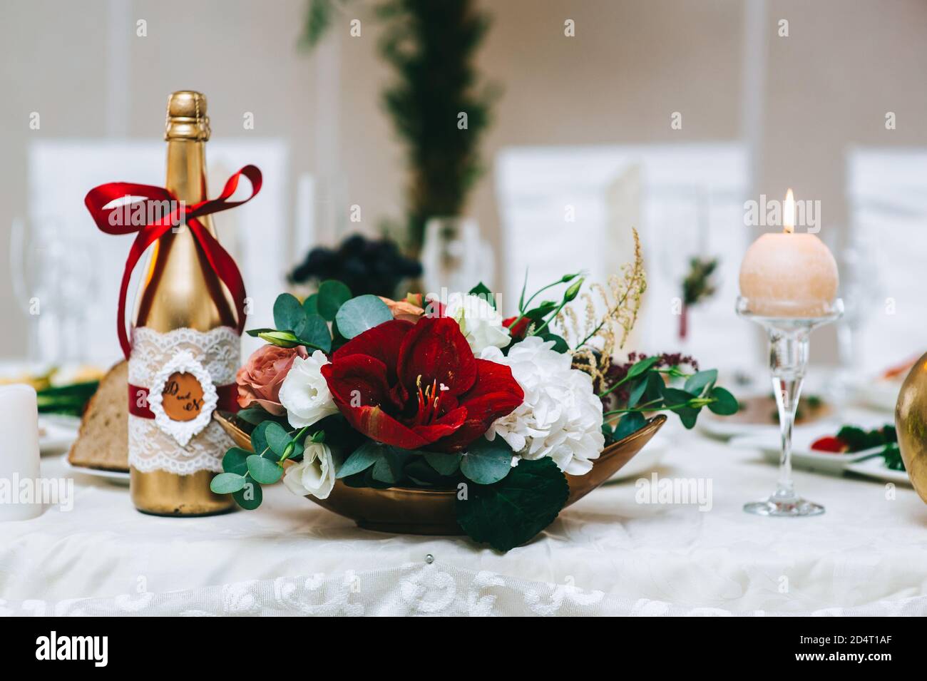 Close up of a flower arrangement in red tones in a gold stand stands on a table. Stock Photo