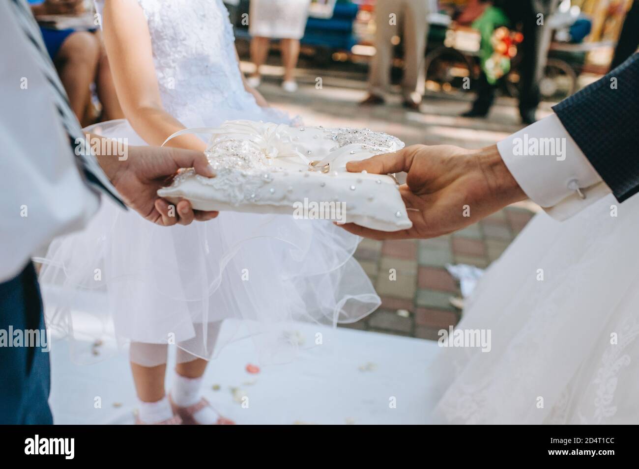 Close up of human hands holding a pillow with wedding rings. Stock Photo