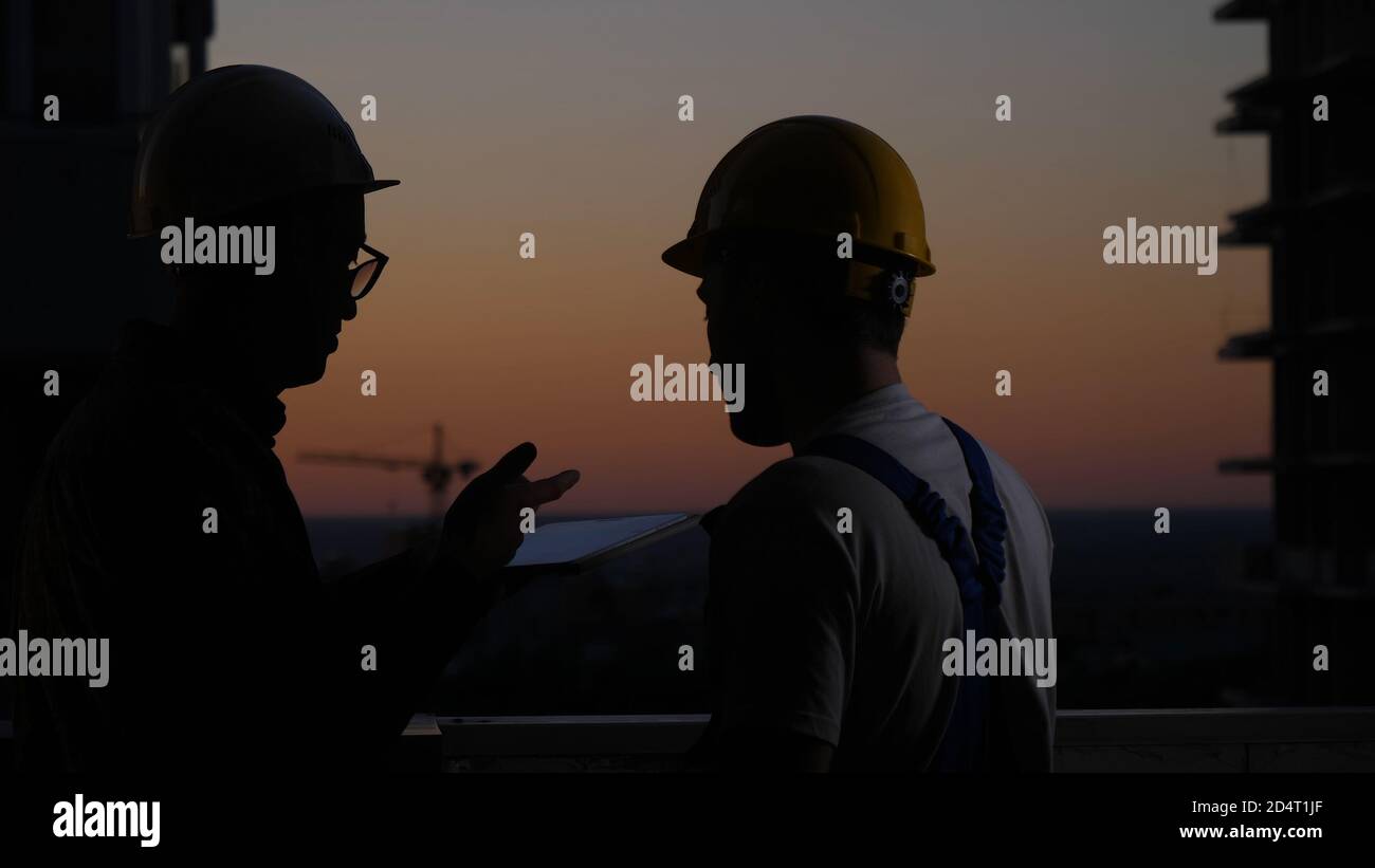 Construction workers using digital tablet at sunset. Stock Photo