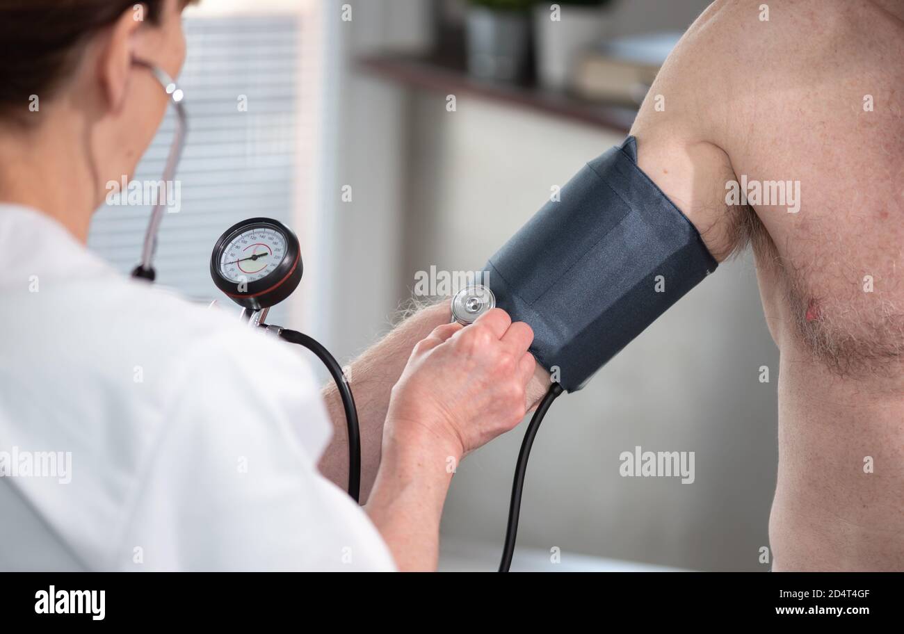Female doctor measuring blood pressure with sphygmomanometer Stock