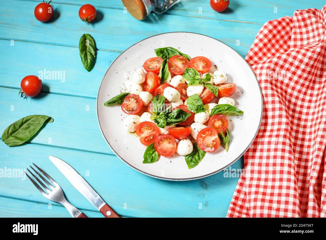 Traditional Italian Caprese Salad - sliced tomatoes, mozzarella cheese and basil on blue wooden background. Stock Photo