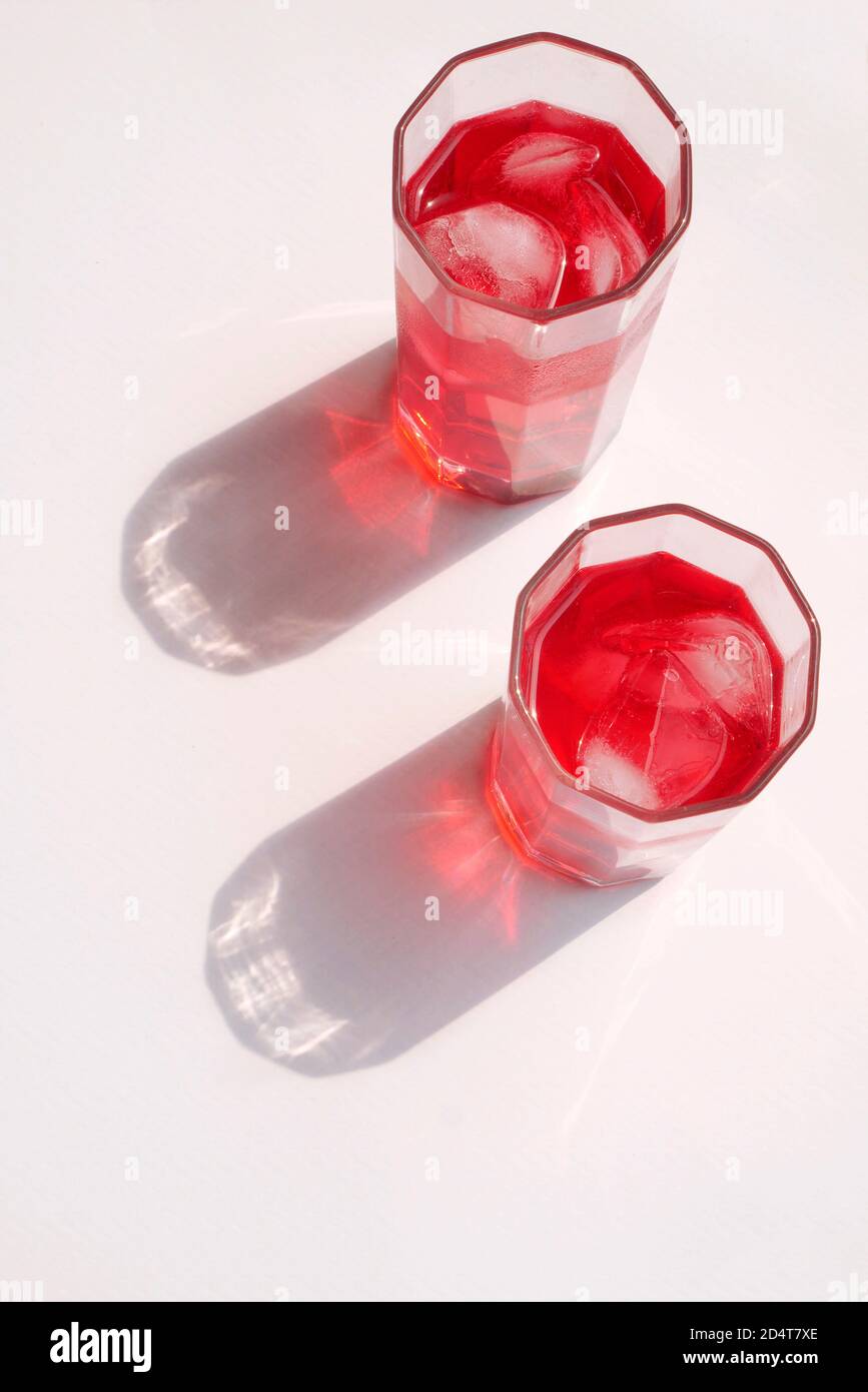 RED SHERBET WITH ICE IN A GLASS WITH A STRONG SHADOW Stock Photo