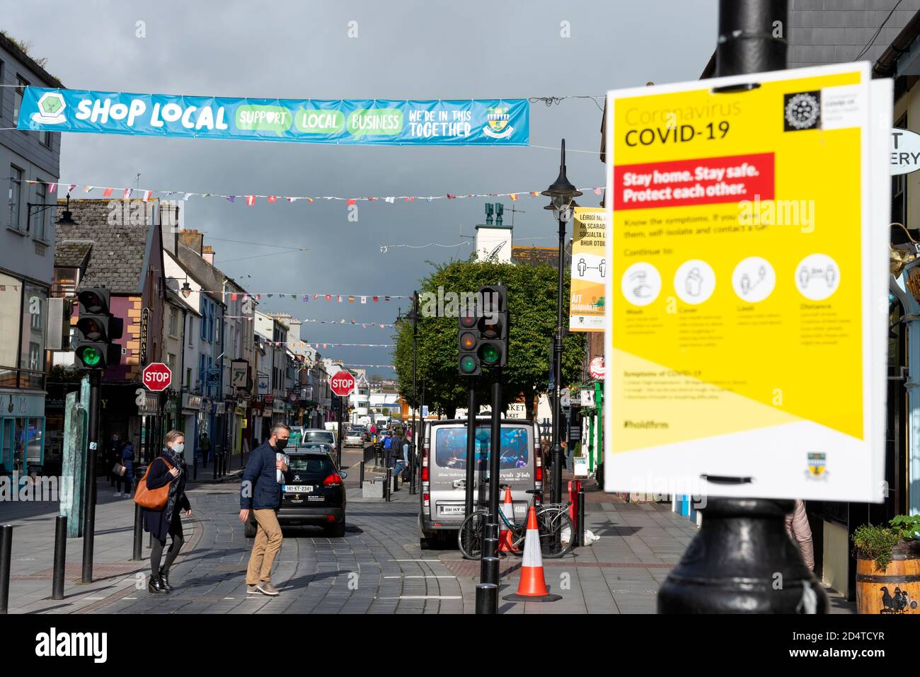 People wearing masks under positive sign for shopping locally to support the local business during Covid 19 pandemic outbreak in Killarney Ireland Stock Photo