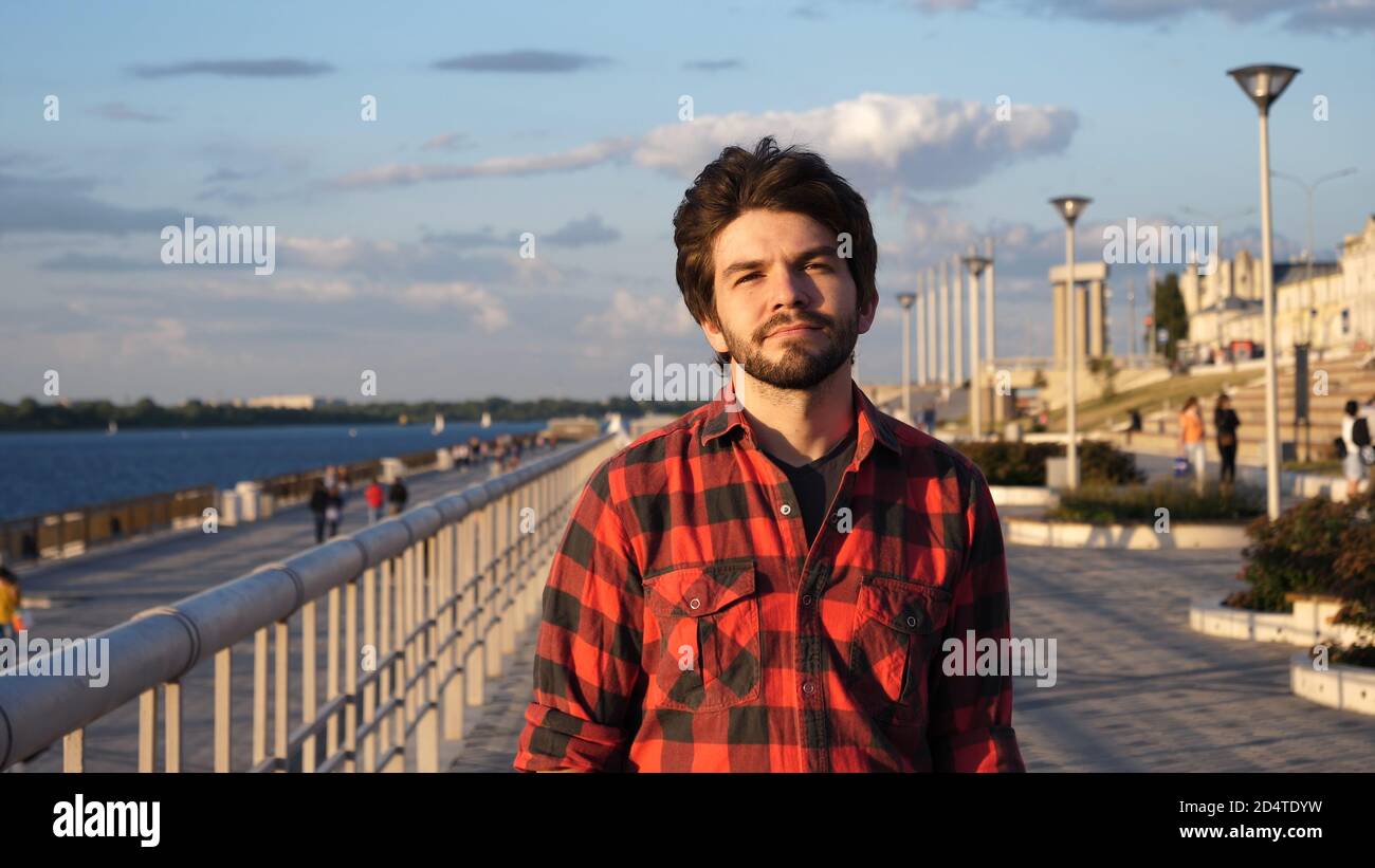 Young man in red shirt walking down the waterfront. Stock Photo