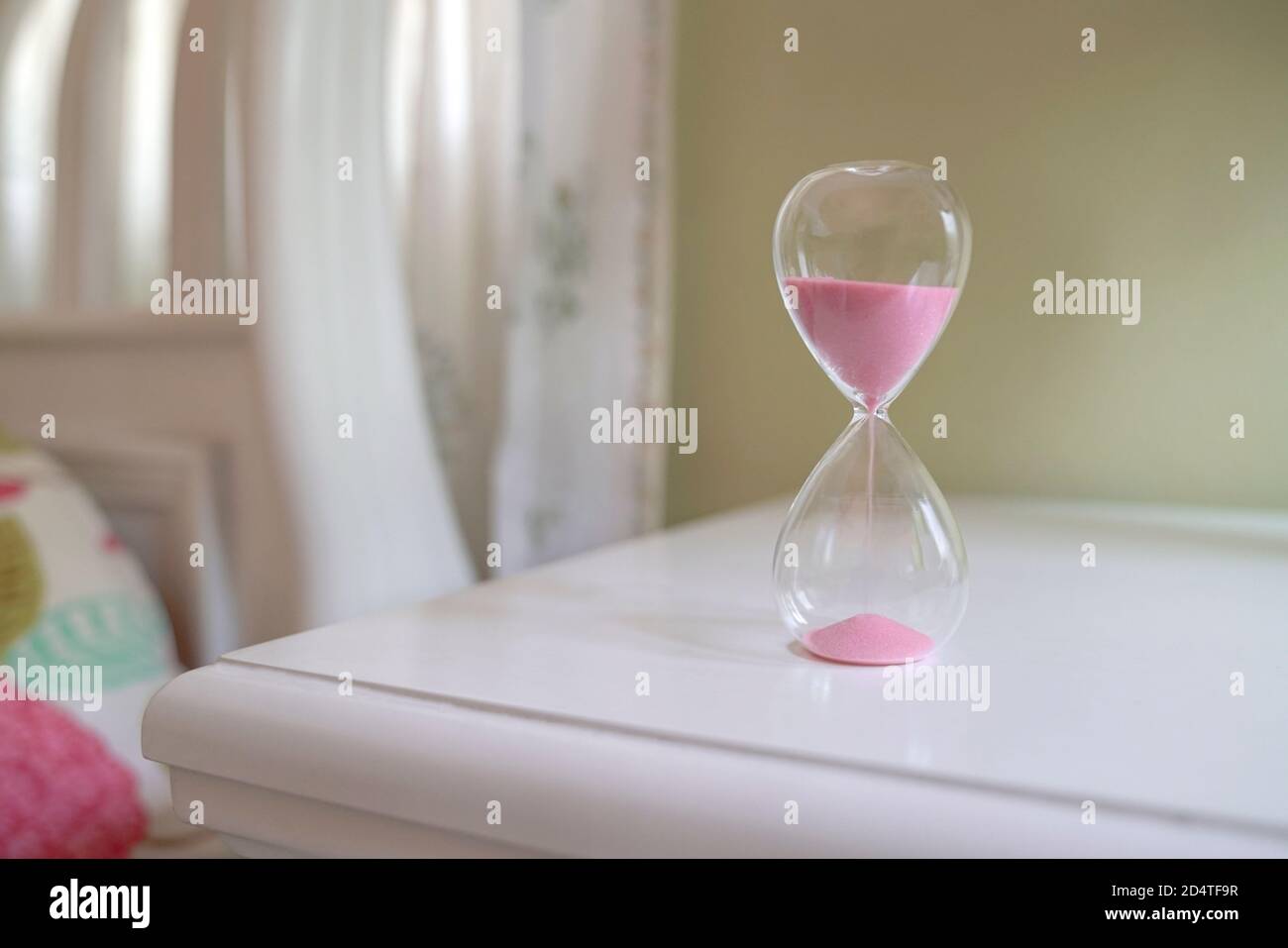 Sand glass on table next to bed. Measuring time passing, countdown or daily routine concept. Stock Photo