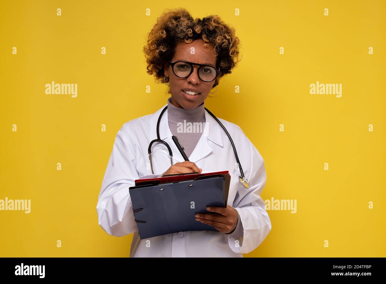 Student doctor wearing white uniform with stethoscope writing something
