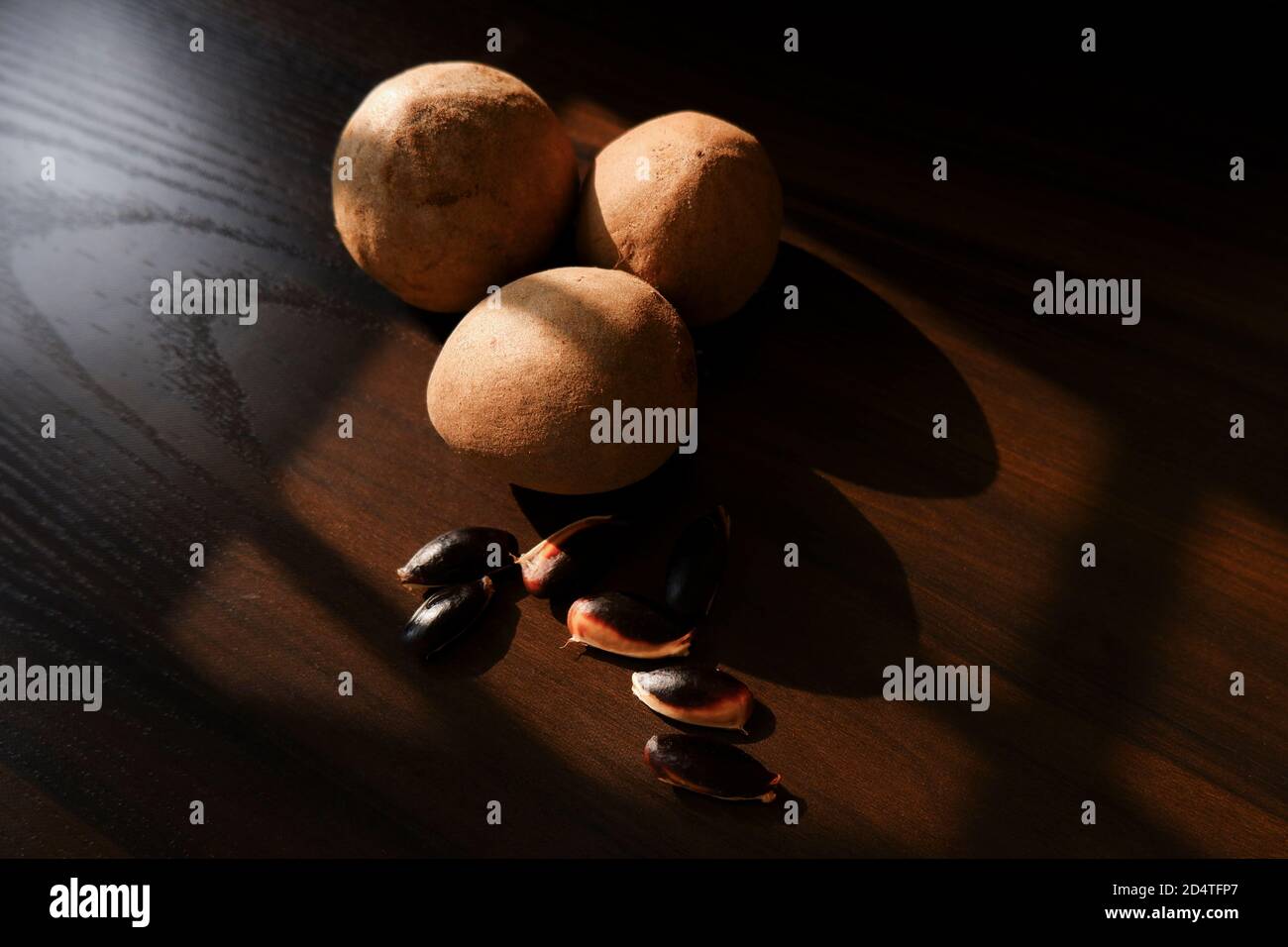 a close shot of sapota (Chikoo) fruits & seeds isolated on wooden background Stock Photo