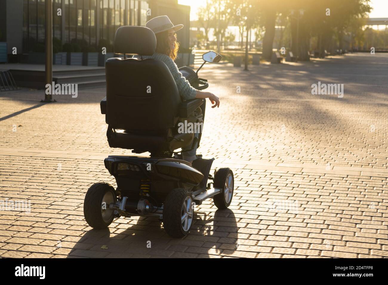Woman tourist riding a four wheel mobility electric scooter on a city street. Stock Photo