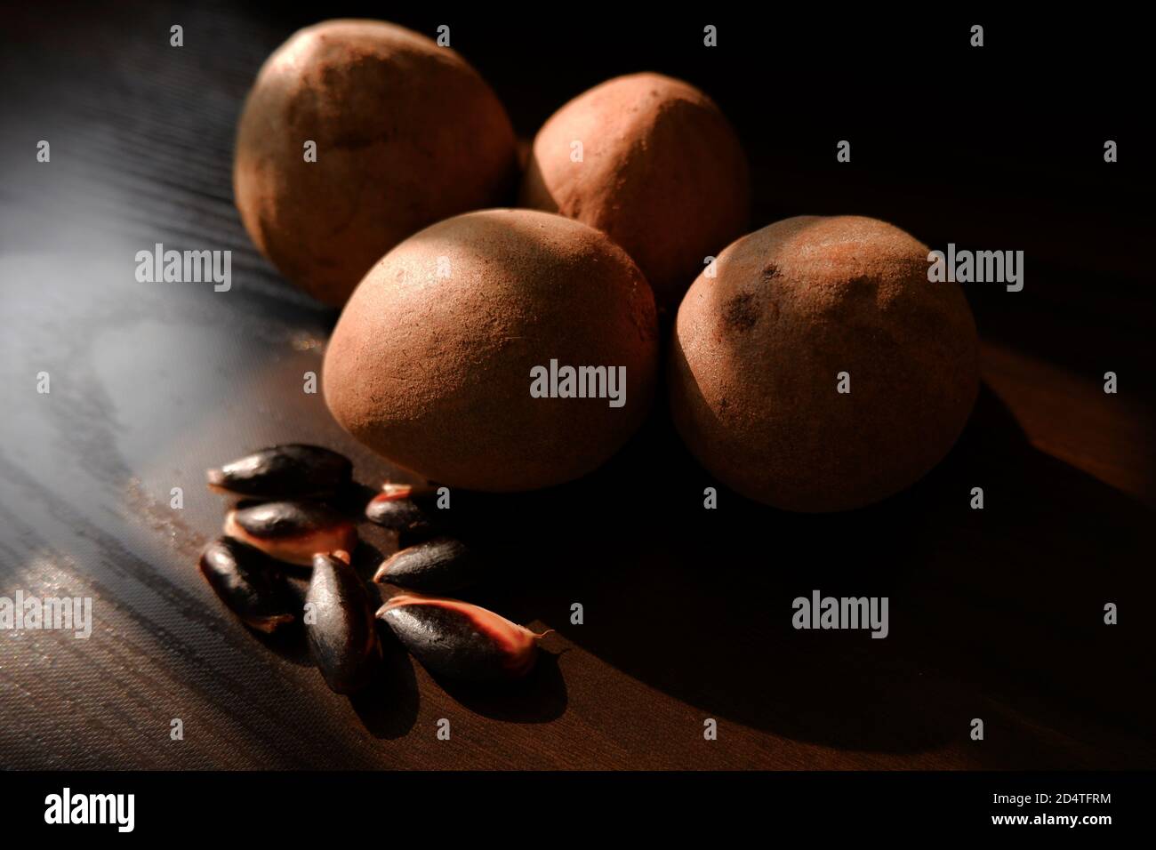 a close shot of sapota (Chikoo) fruits & seeds isolated on brown wooden background Stock Photo