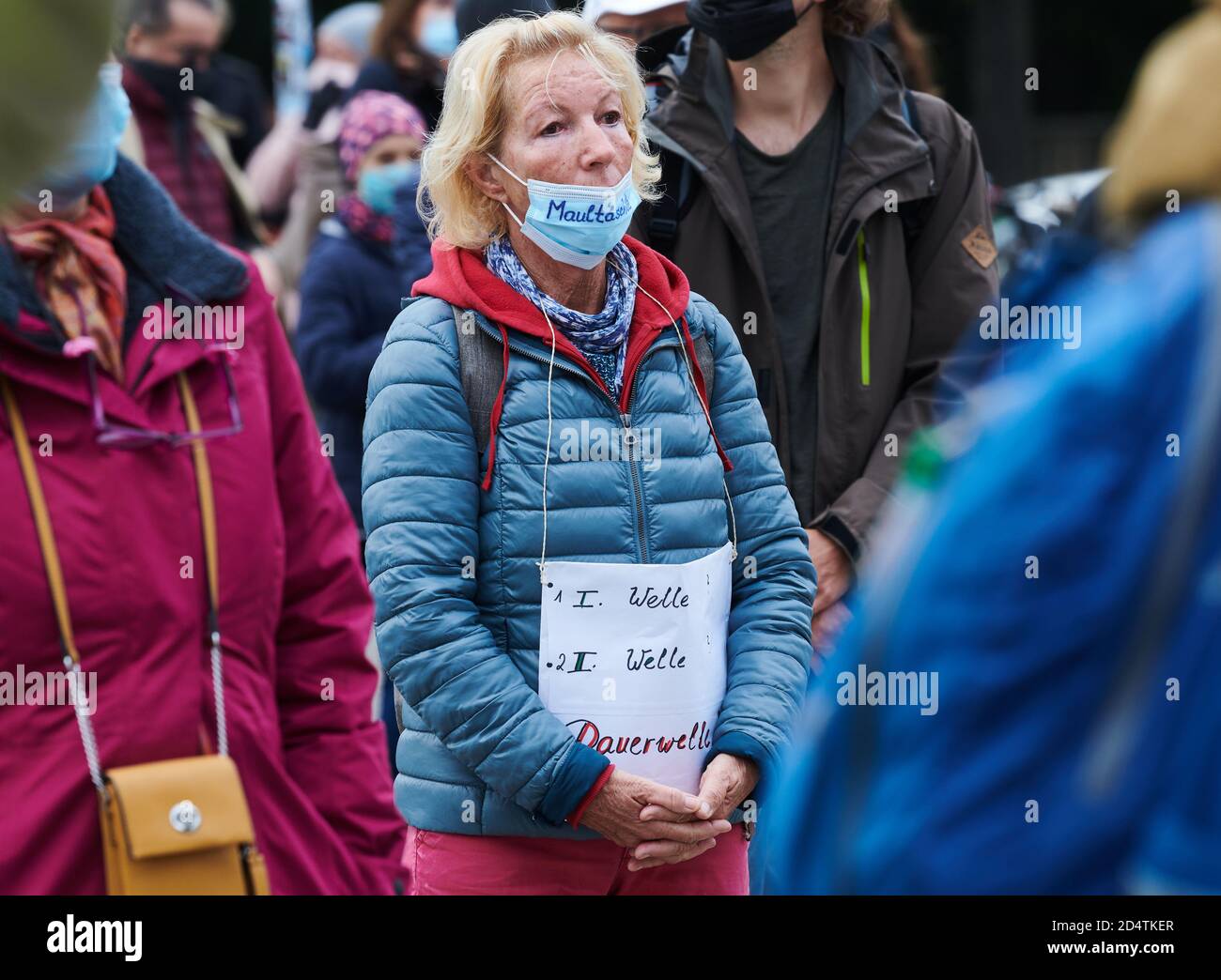 Berlin, Germany. 11th Oct, 2020. '1st wave - 2nd wave - permanent wave' is written on the poster that a demonstrator hung around her stomach during the lateral thinking demonstration in front of the Brandenburg Gate. 'Maultäschle' is written on her mouth guard. Credit: Annette Riedl/dpa/Alamy Live News Stock Photo