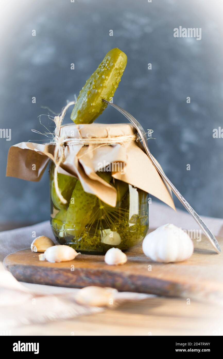 Homemade jars of pickled cucumbers with garlic on a rustic wooden