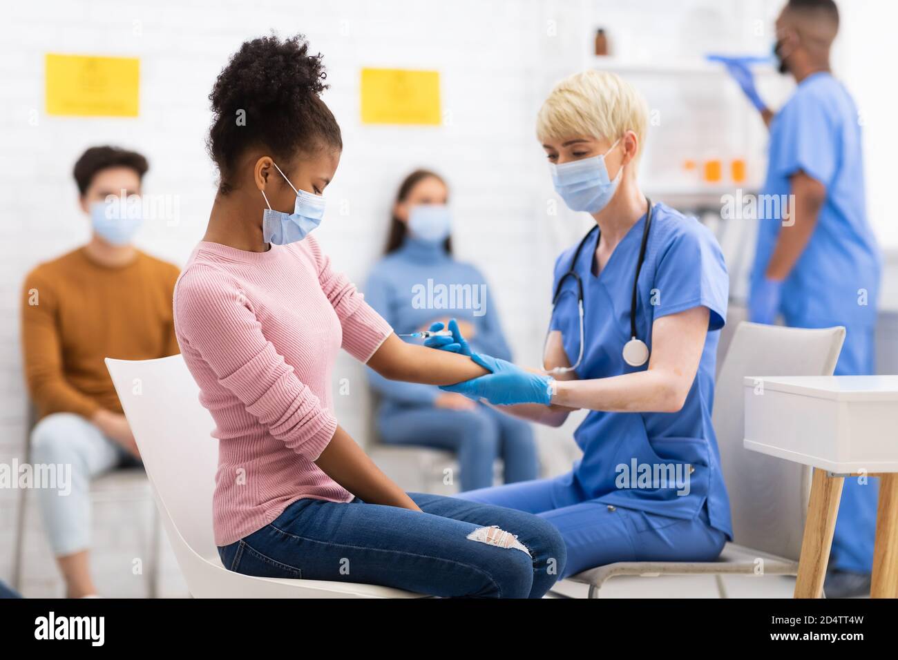 Nurse Vaccinating African Girl Against Covid-19 Injecting Vaccine In Hospital Stock Photo