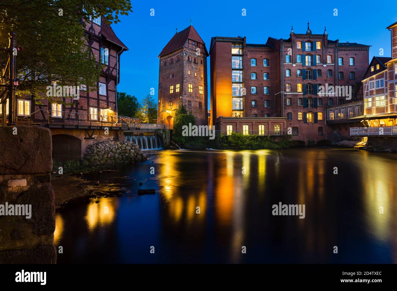 Old mill and hotel at the Ilmenau River in the old town of Lueneburg, Germany with night blue sky. Stock Photo