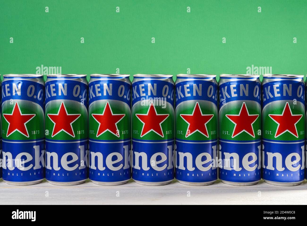 Varna, Bulgaria, October 09, 2020. Row of Heineken 0.0 beer cans with red star on a white wood table against green wall. Nonalcoholic malt lager. Stock Photo