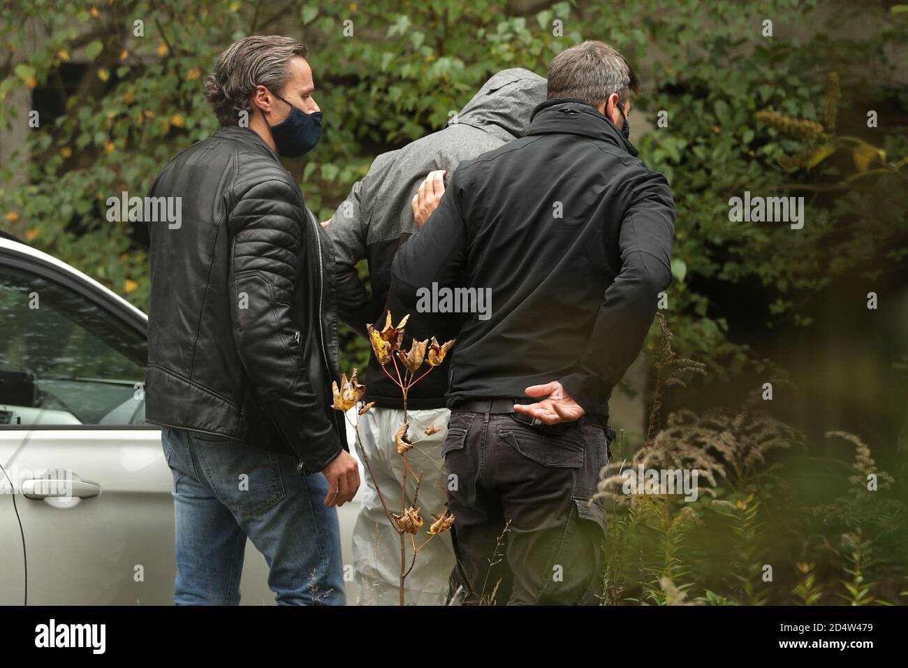 Duisburg, Germany. 11th Oct, 2020. Two policemen lead a suspect in their midst during an inspection at the place where a girl had been found dead. The 14-year-old girl was the victim of a crime. Credit: David Young/dpa/Alamy Live News Stock Photo