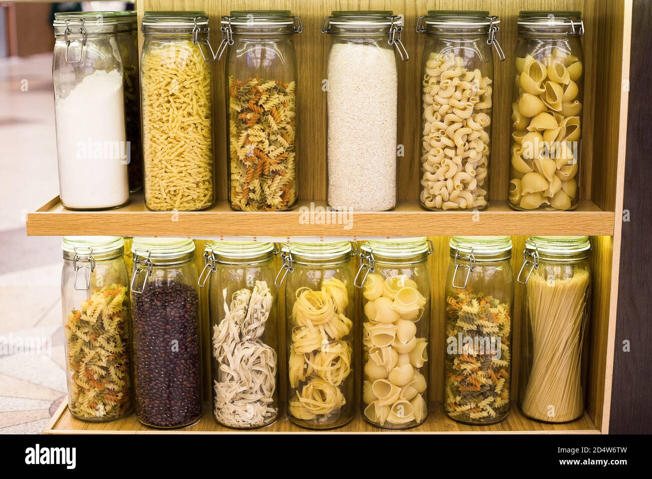 Different types of raw pasta spaghetti, fettuccine, pappardelle, fusilli, cavatappi, pipe rigate, gemelli and cereals beans, rice are stored in closed Stock Photo
