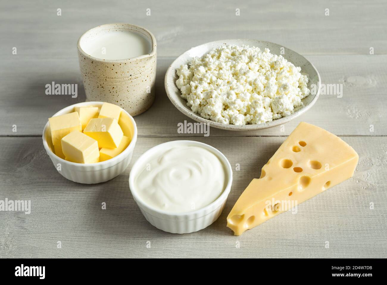 Most common dairy products are butter, cheese, milk, sour cream, cottage cheese in a white dish on a white wooden background close up. Natural, organi Stock Photo