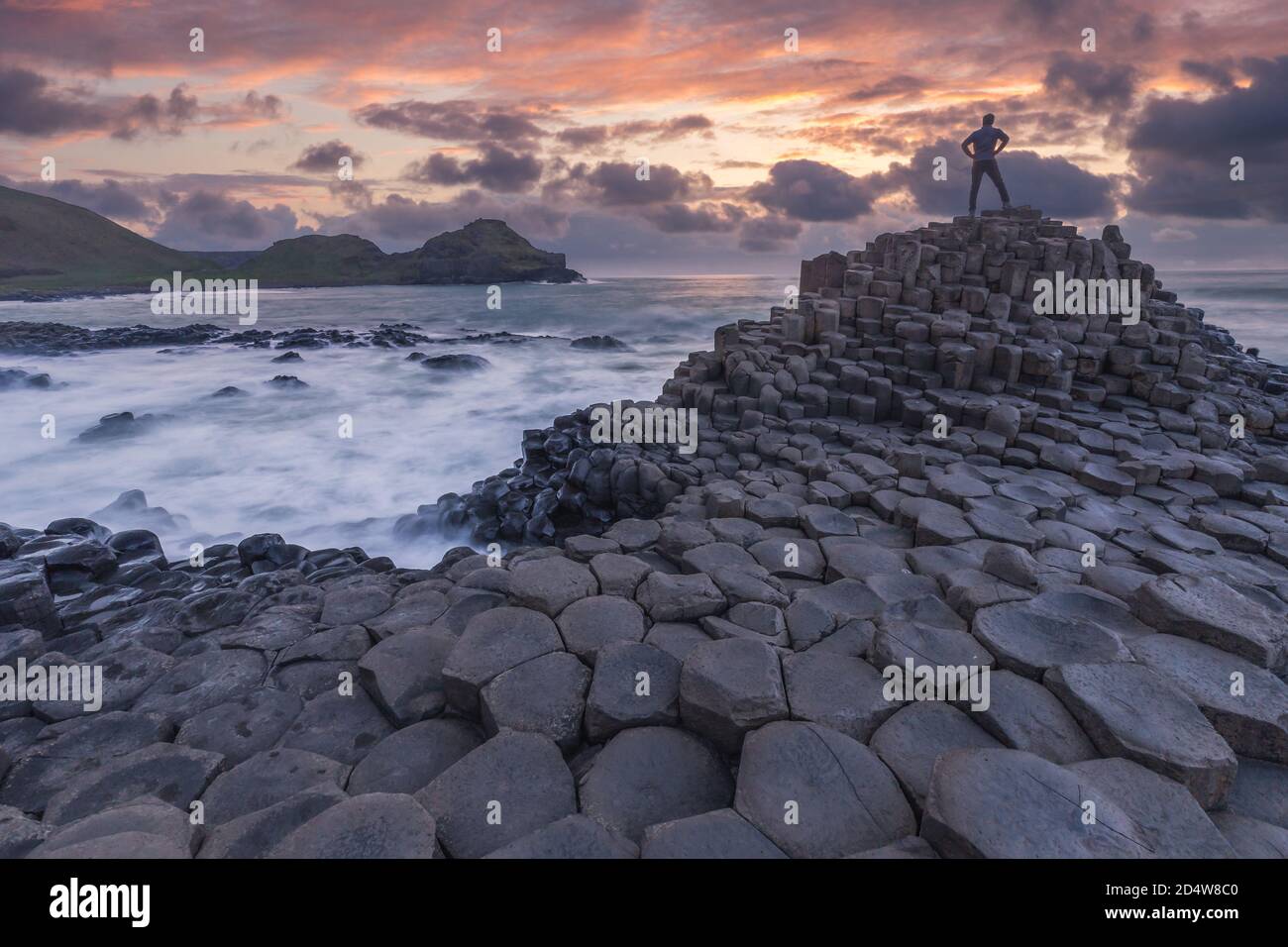 Silhouette of one person standing at Giant Causeway rocks at sunset in ...
