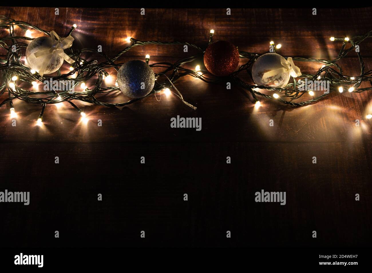 christmas balls with lights on a wooden base. christmas decoration. low key photography Stock Photo