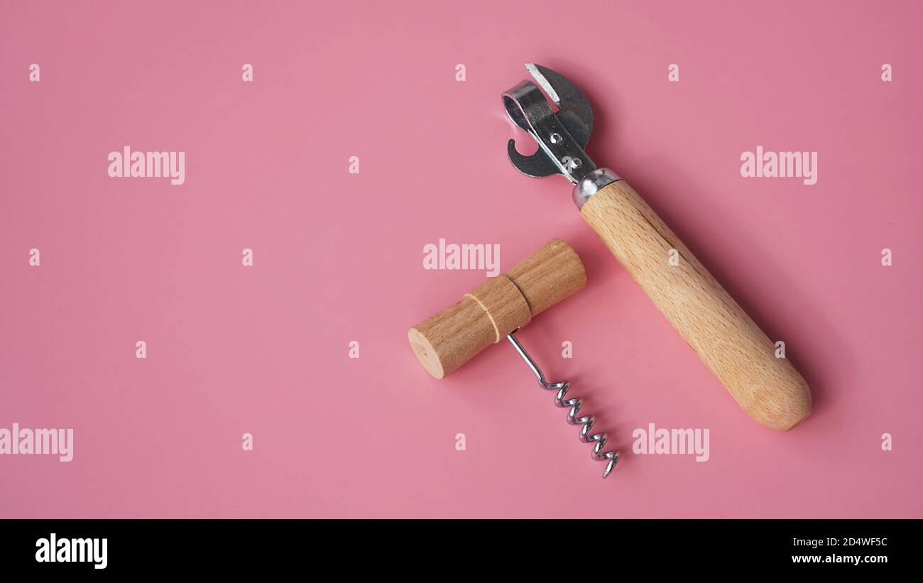 Wooden corkscrews and tin opener on pink background Stock Photo