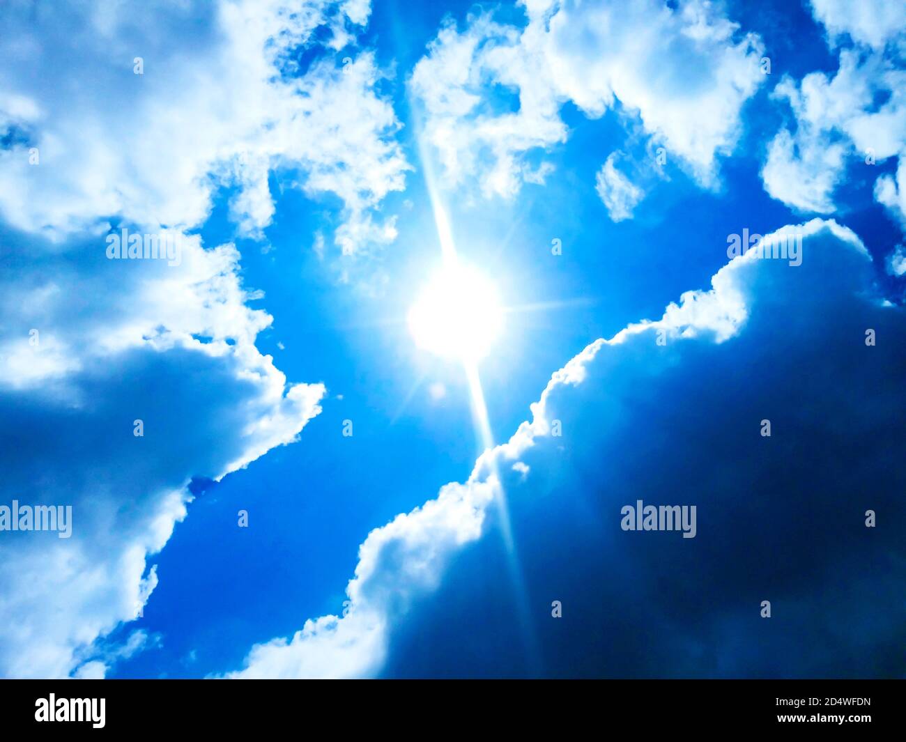 Sunny background, blue sky with white clouds and sun Stock Photo