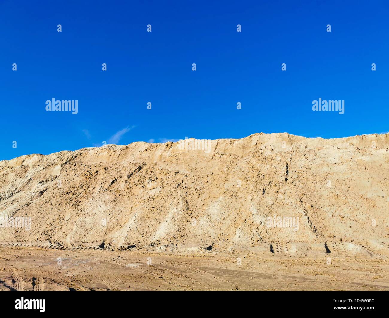 A mountain of wet yellow sand and a blue, clear sky. Stock Photo