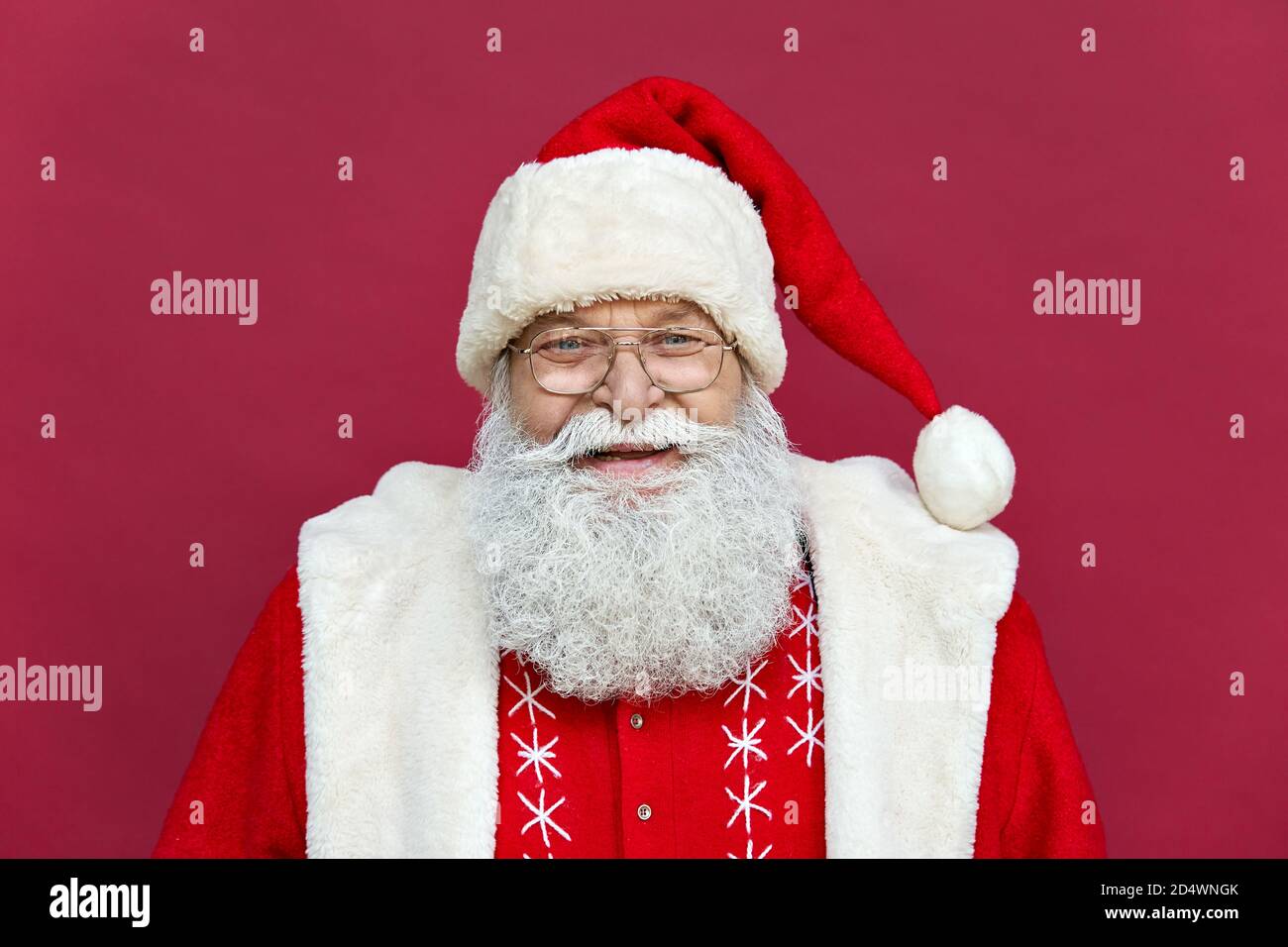 Happy old Santa Claus looking at camera standing on red background, headshot. Stock Photo