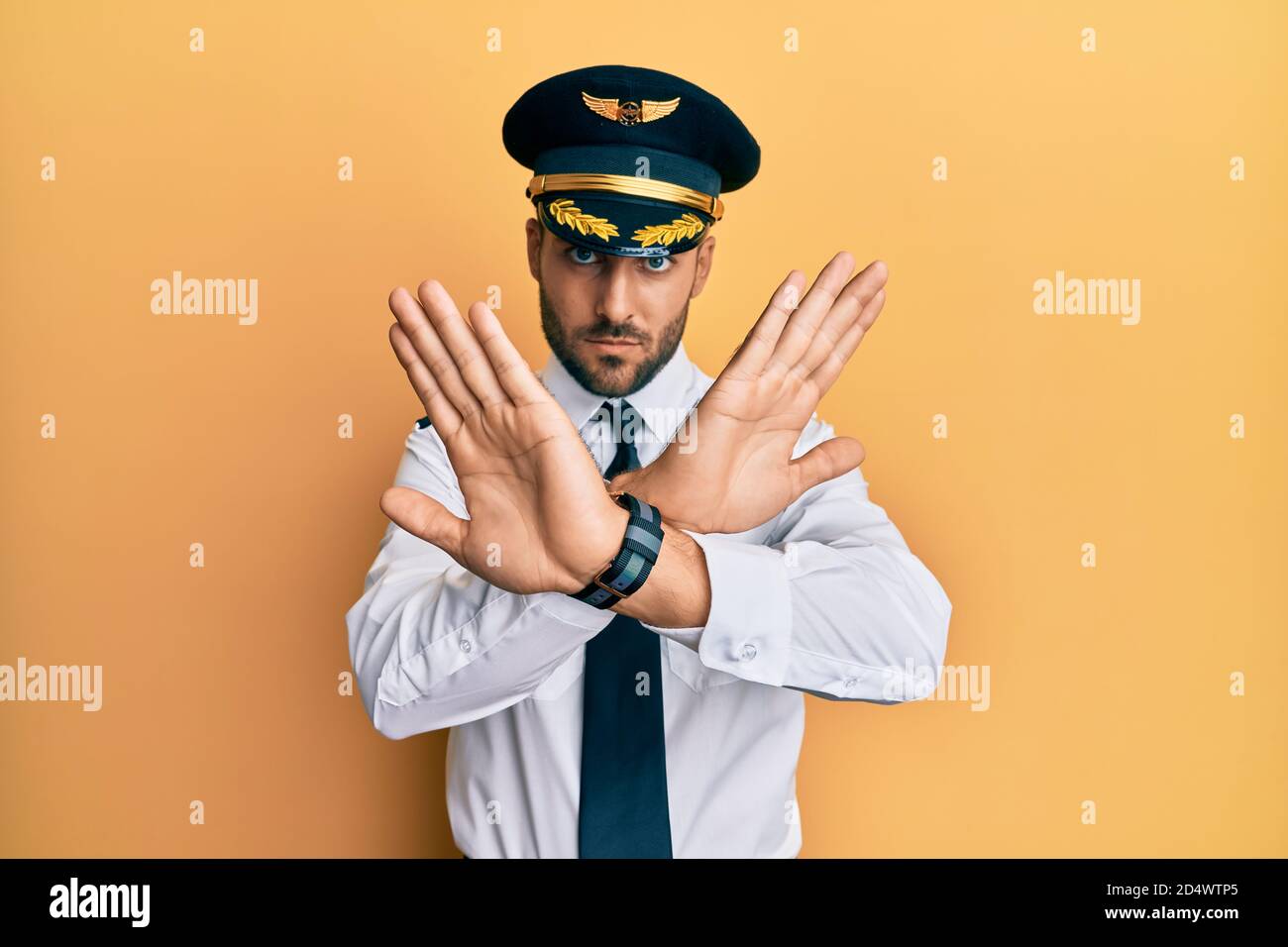 Handsome hispanic man wearing airplane pilot uniform rejection ...