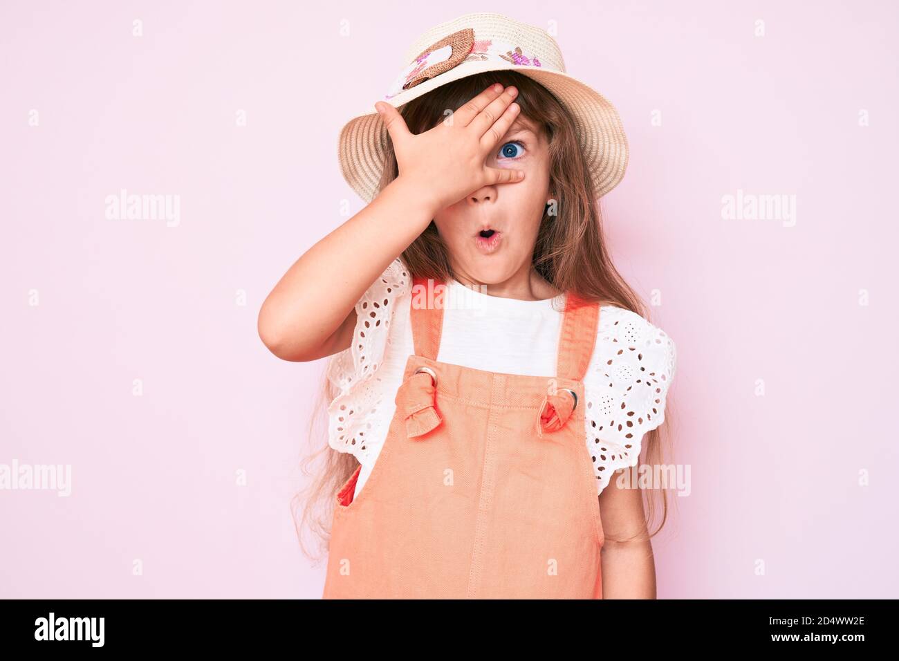 Little caucasian kid girl with long hair wearing spring hat peeking in ...