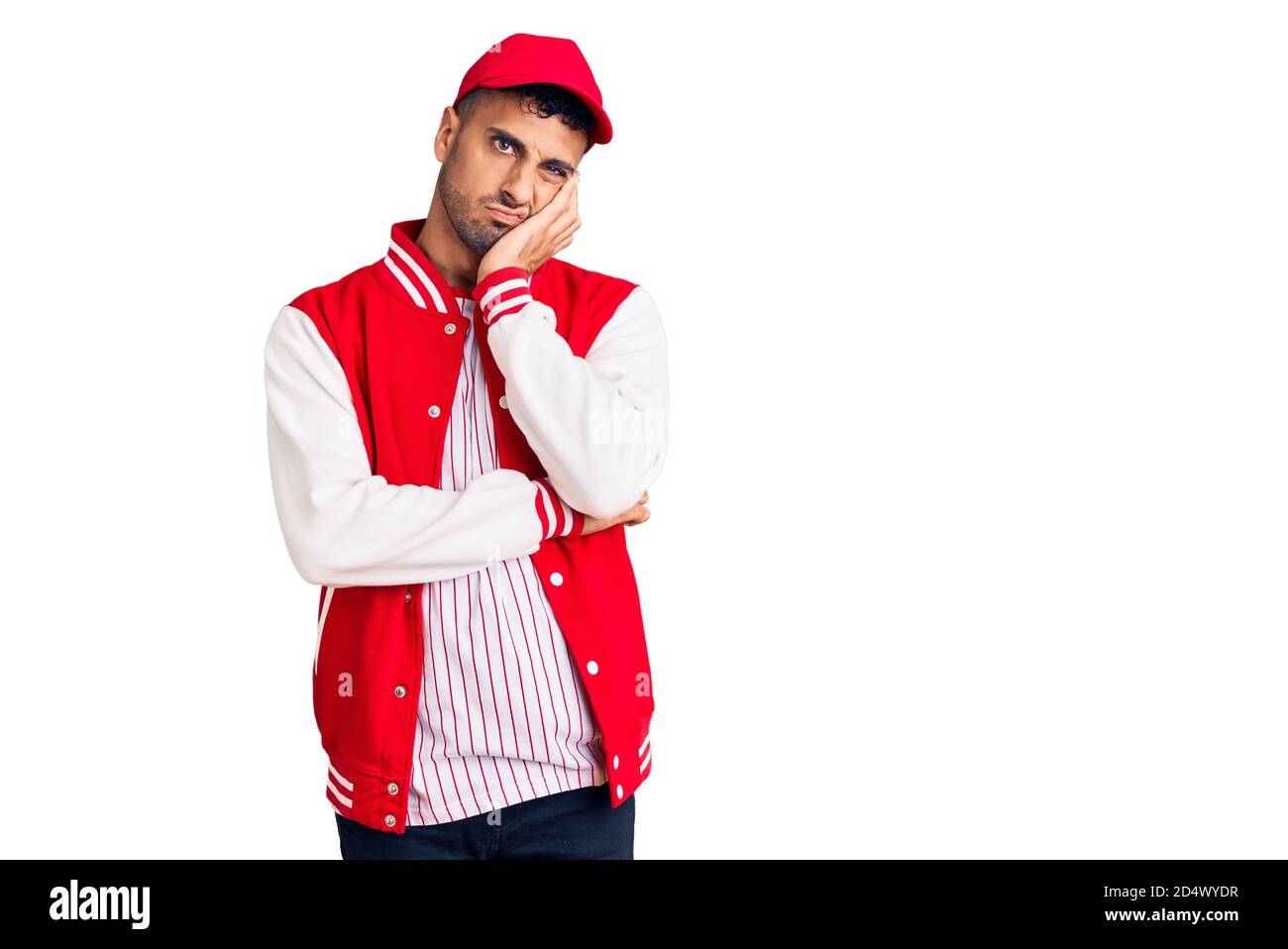 Young hispanic man wearing baseball uniform thinking looking tired and bored with depression problems with crossed arms. Stock Photo