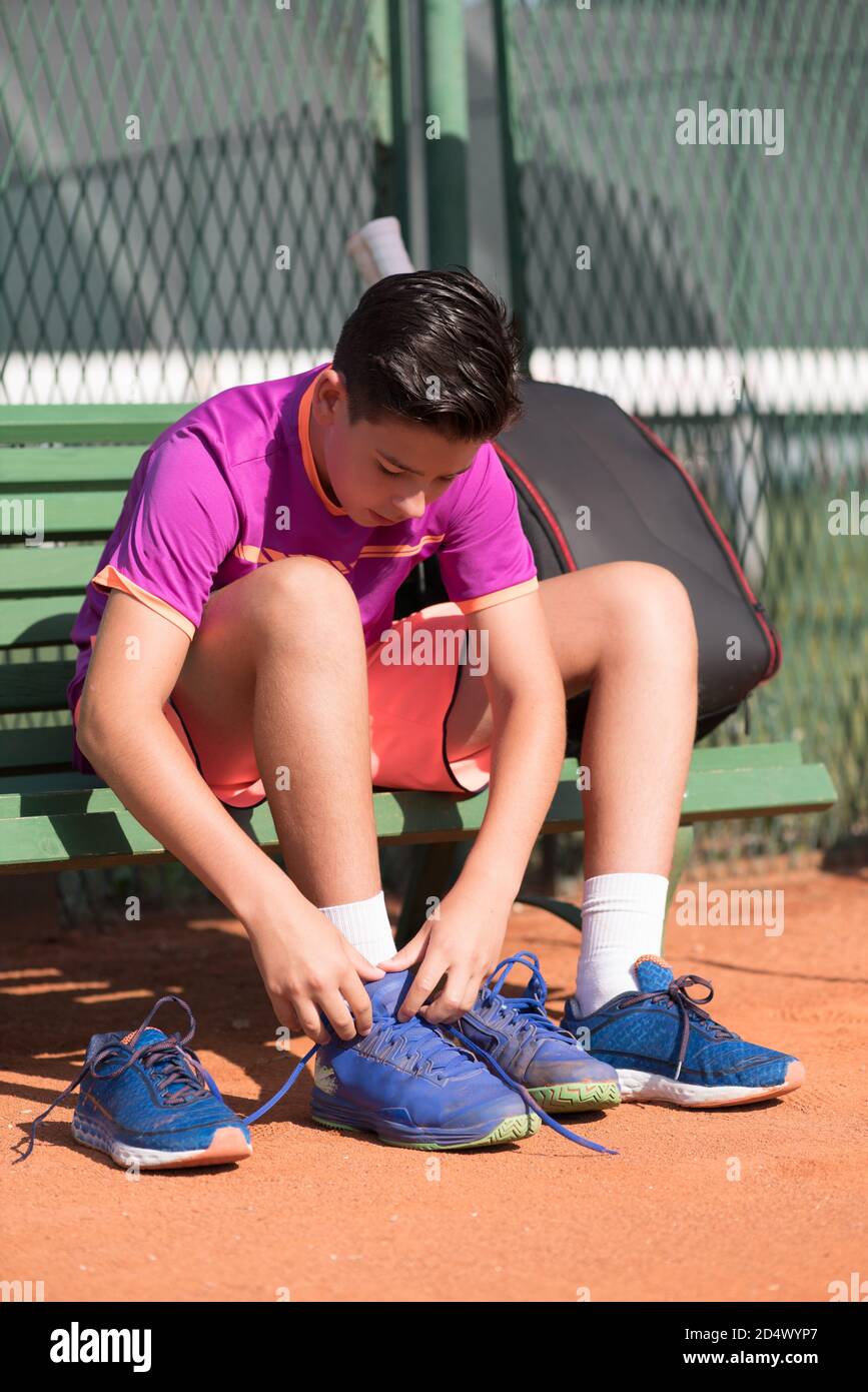 Young tennis player prepares for the match. Tying shoelaces. Stock Photo