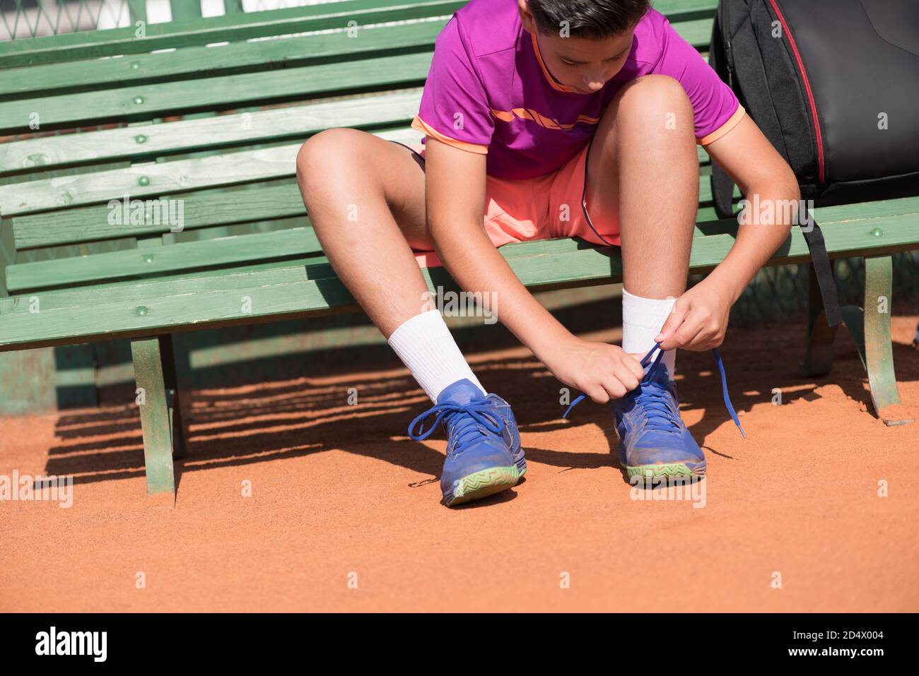 Young tennis player prepares for the match. Tying shoelaces. Stock Photo
