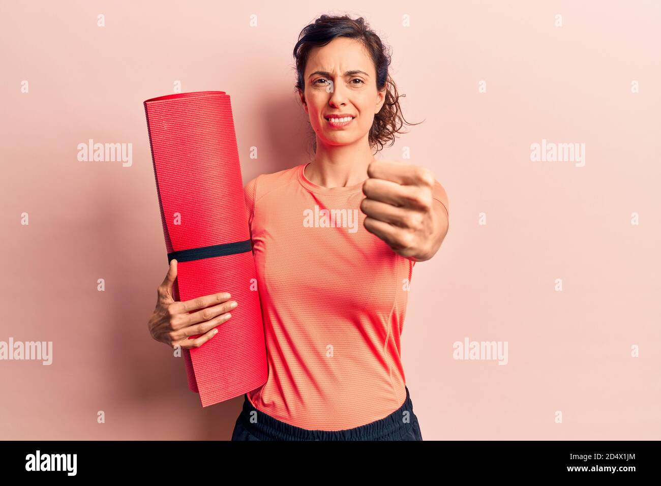 Young beautiful hispanic woman holding yoga mat annoyed and frustrated ...