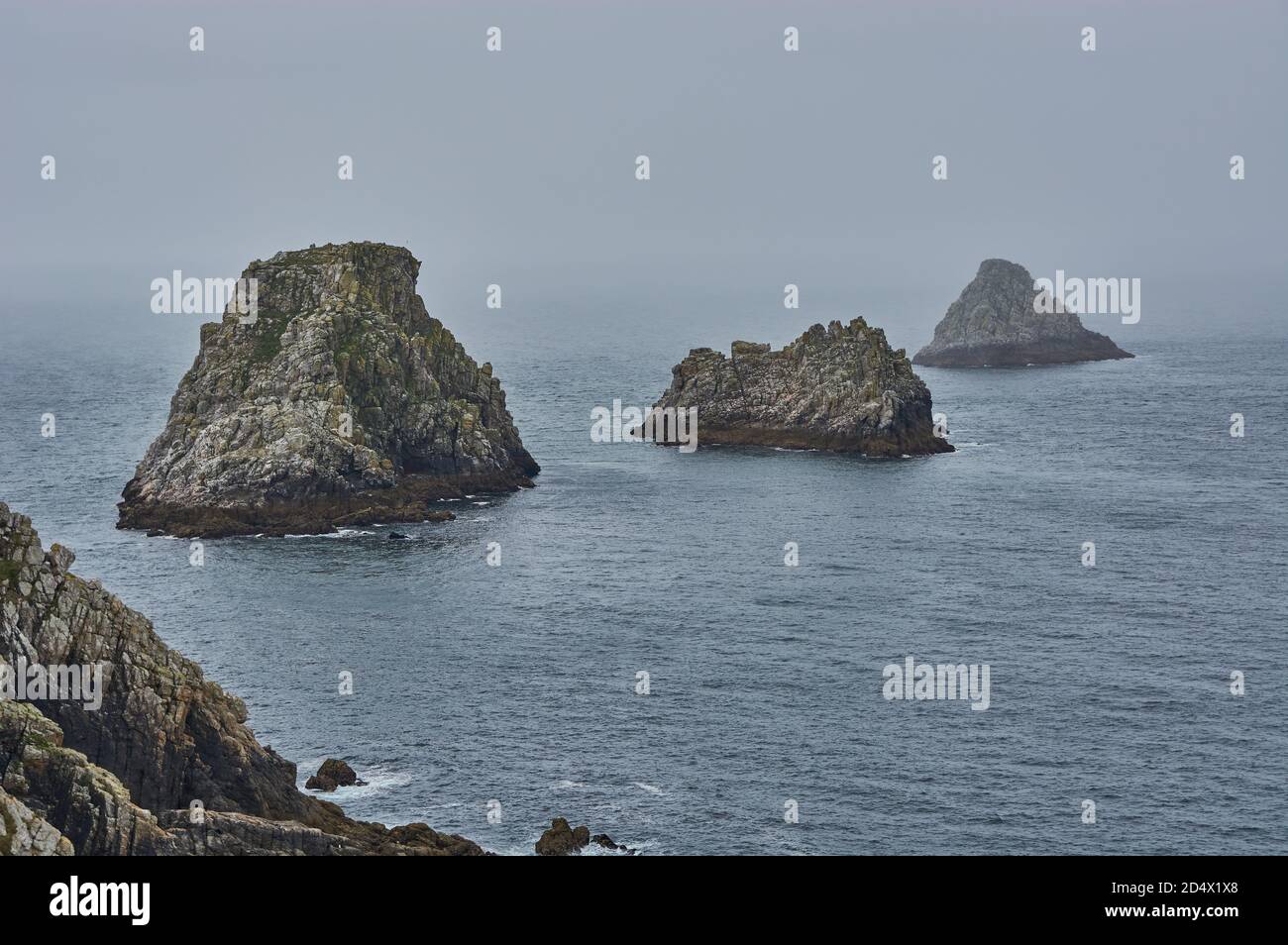 Mystical rock formation in the misty atlantic ocean. Rocky islands at the coastline of Brittany, France. Stock Photo