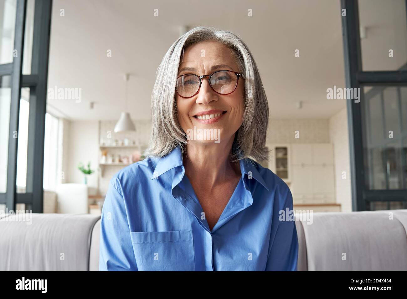 Smiling mature older woman looking at camera, webcam headshot. Stock Photo