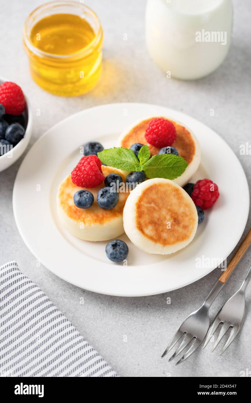 Cottage cheese fritters Syrniki served with summer berries and honey. Russian, Ukrainian cuisine food Stock Photo