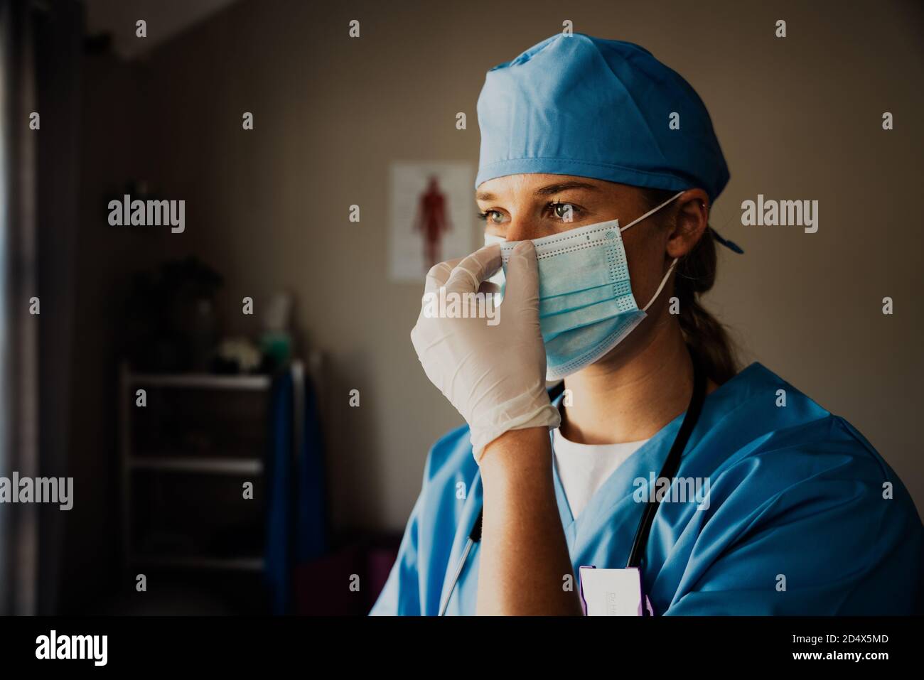 female nurse dressing up in surgical gloves and scrubs preparing to see sick patient in clinic Stock Photo Alamy