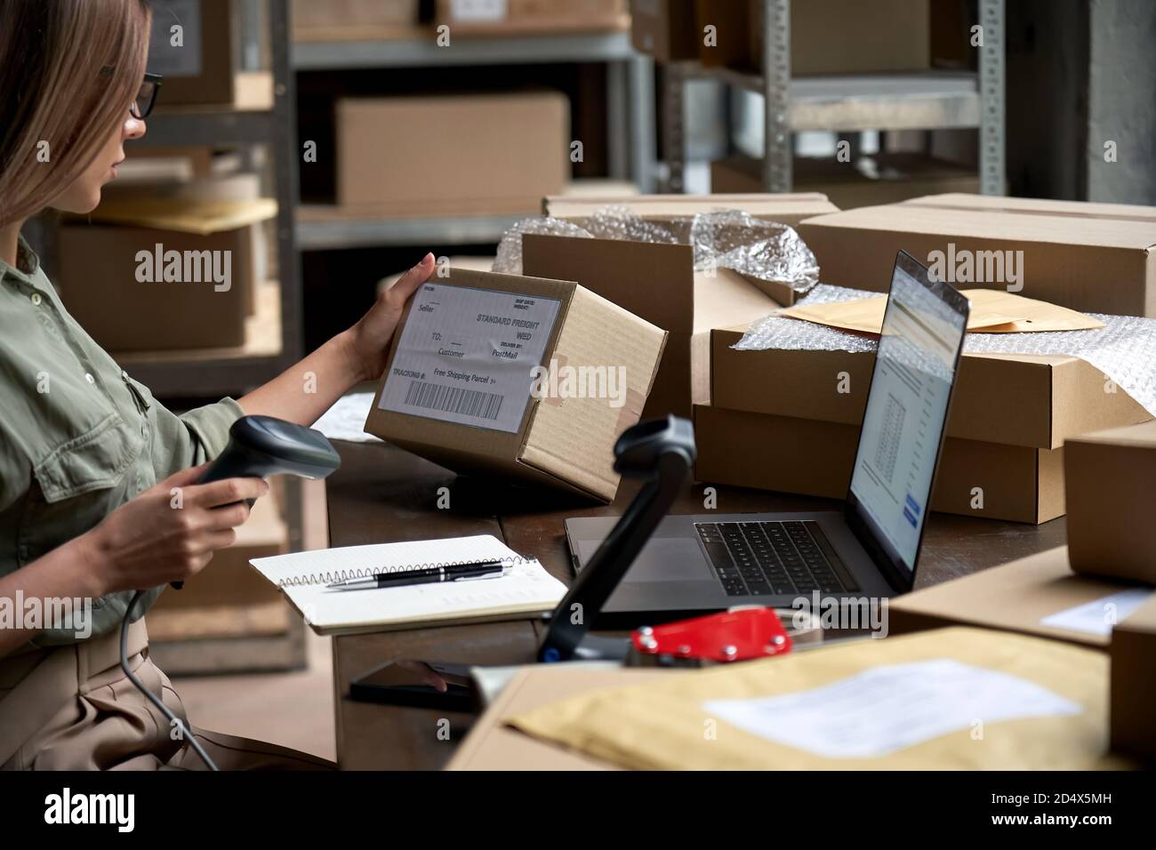 Female seller scanning ecommerce shipping box in dropshipping warehouse. Stock Photo