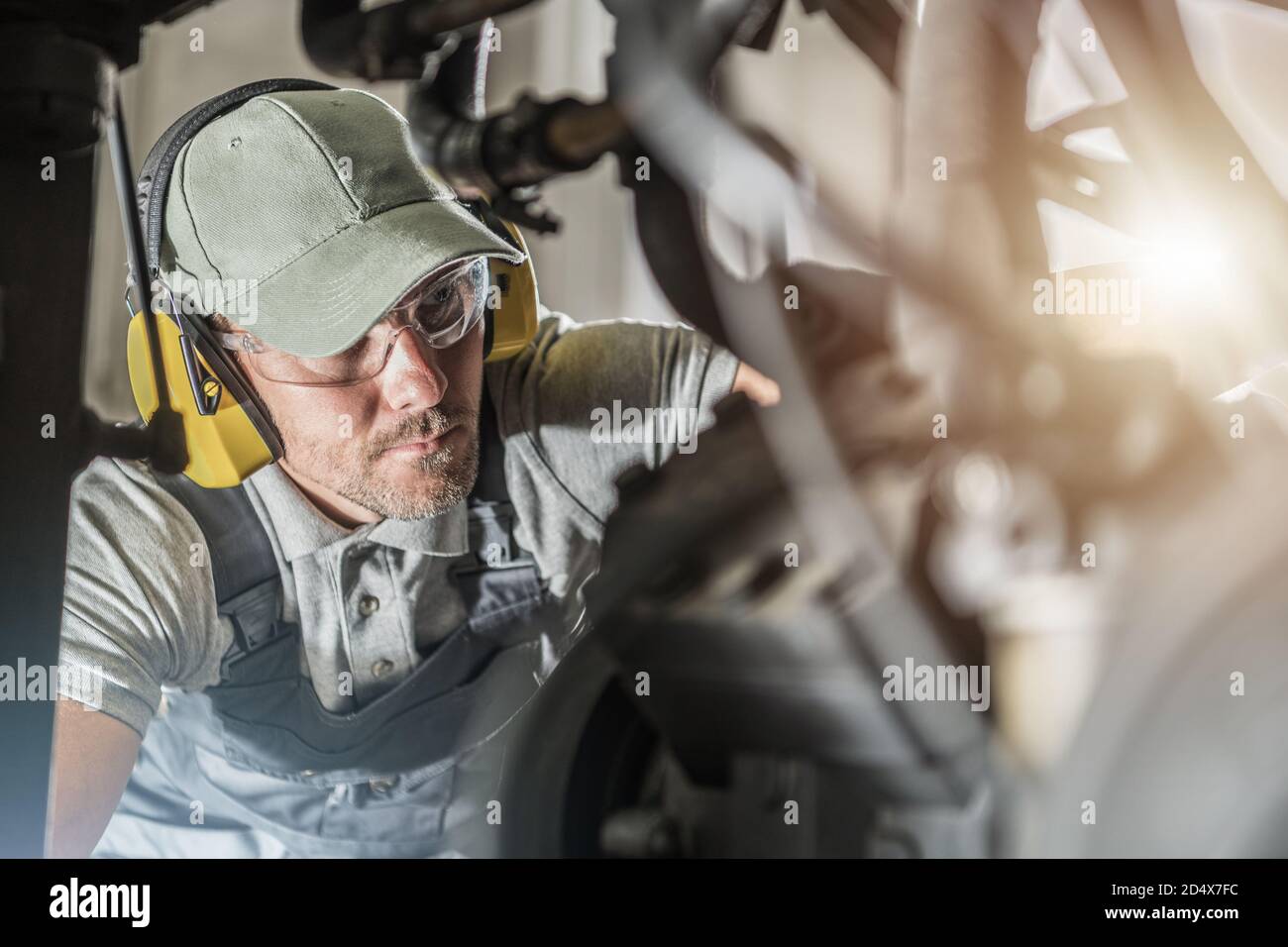 Caucasian Automotive Industry Technician in His 40s Wearing Safety Glasses Looking Into Engine Compartment To Spot Potential Issue with the Vehicle Po Stock Photo