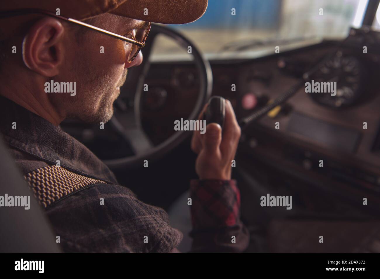 Two Way CB Radio Convoy Communication. Caucasian Trucker in His 40s Making Conversation Using Built In Truck Cabin Radio. Transportation and Communica Stock Photo