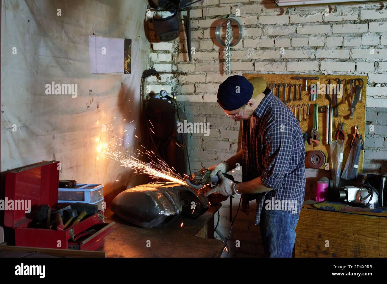 Man grinding motorbike fuel tank part in workshop horizontal shot Stock Photo