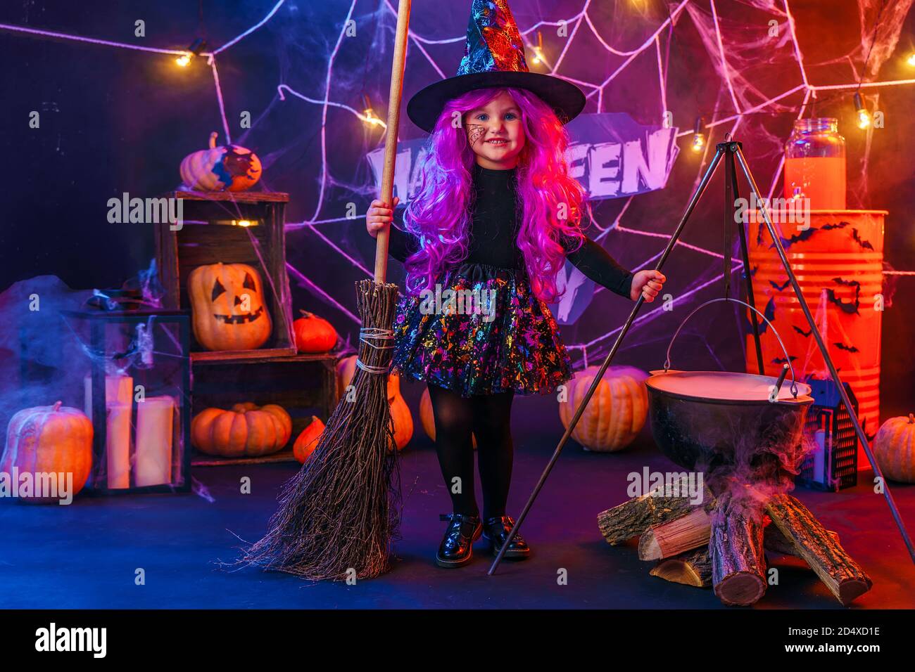 Little beautiful girl in a witch costume celebrates Happy Halloween party  by brew a potion in a steaming vat, interior with pumpkins Stock Photo -  Alamy