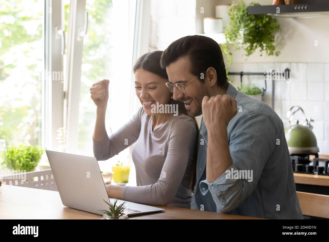 Overjoyed young married couple making yes gesture, looking at computer. Stock Photo