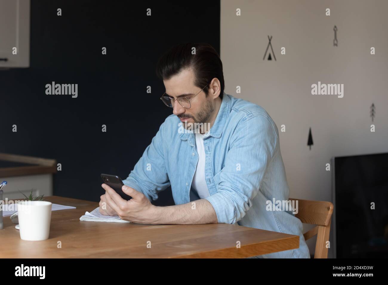 Focused young man using smartphone at home. Stock Photo