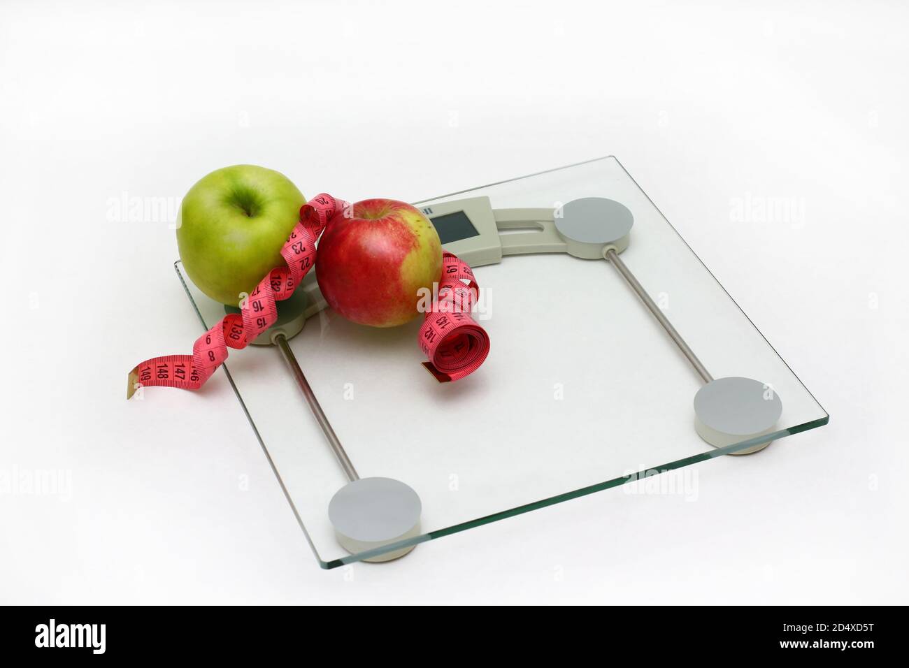 https://c8.alamy.com/comp/2D4XD5T/two-fresh-apples-green-and-red-with-measuring-ribbon-lie-on-glass-floor-scales-white-bachground-2D4XD5T.jpg