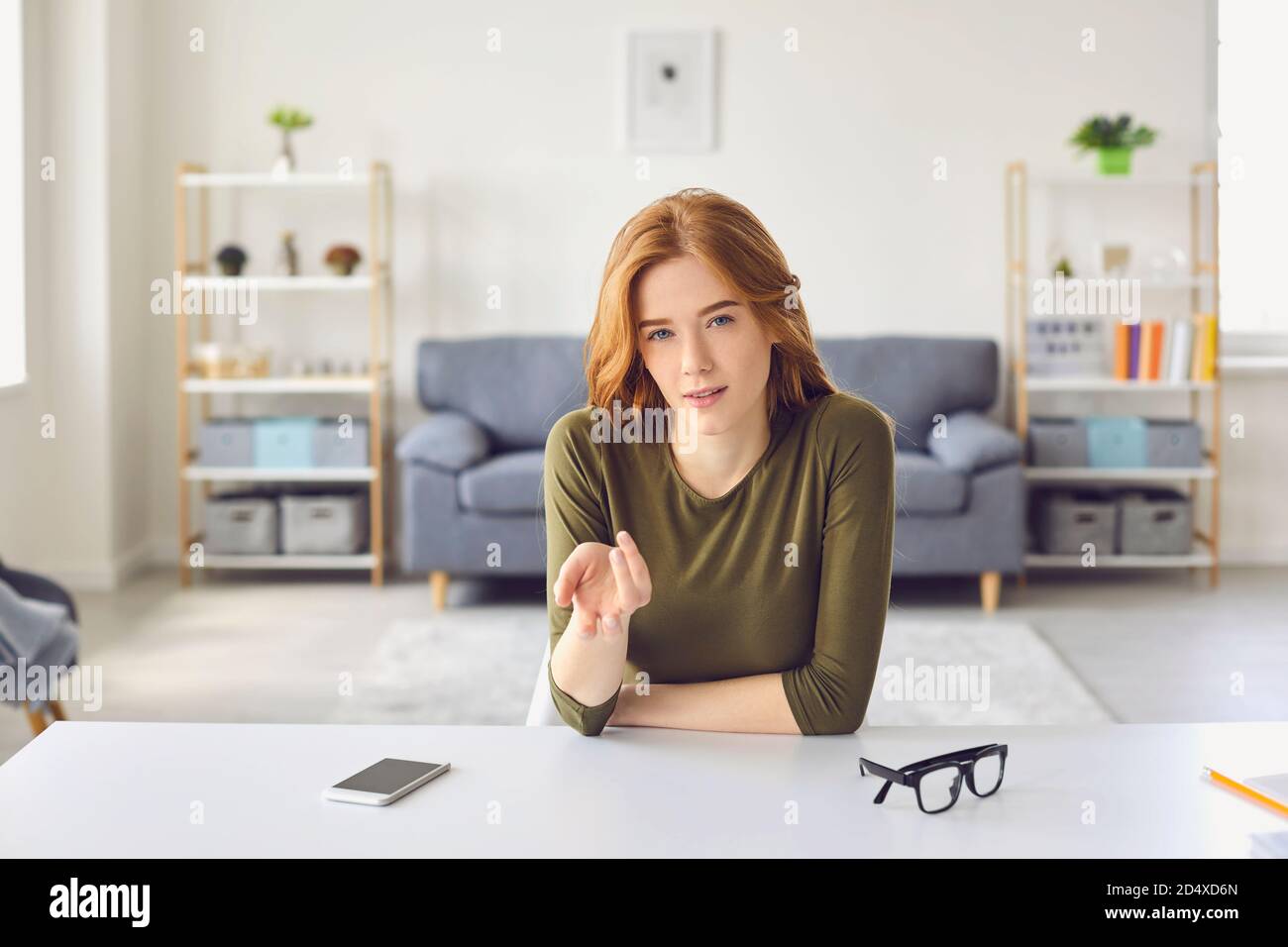 Beautiful teen girl talking and looking at the camera while making a video blog or video call. Stock Photo