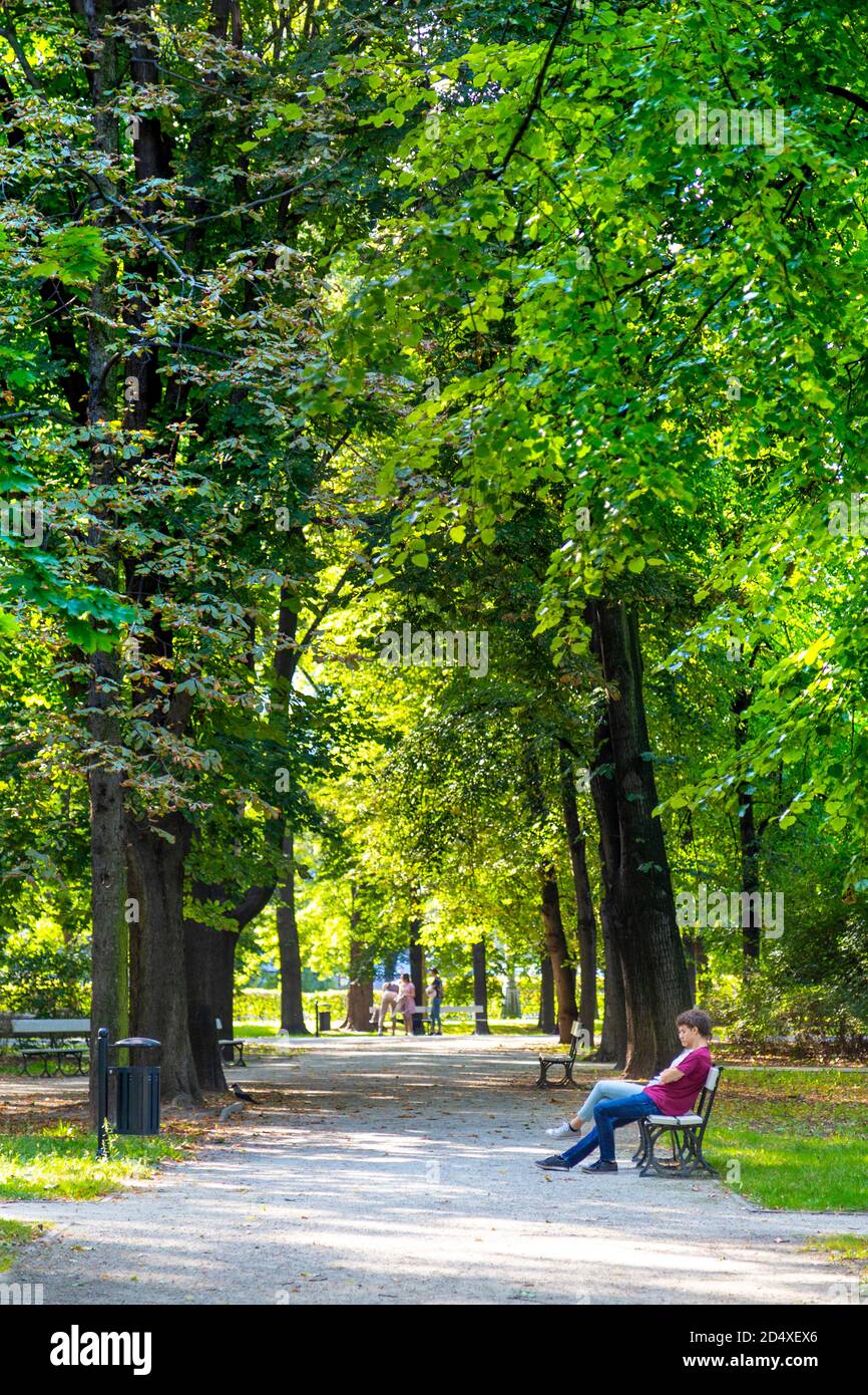 Alley and people sitting on a park bench at Saxon Garden (Ogrod Saski), Warsaw, Poland Stock Photo
