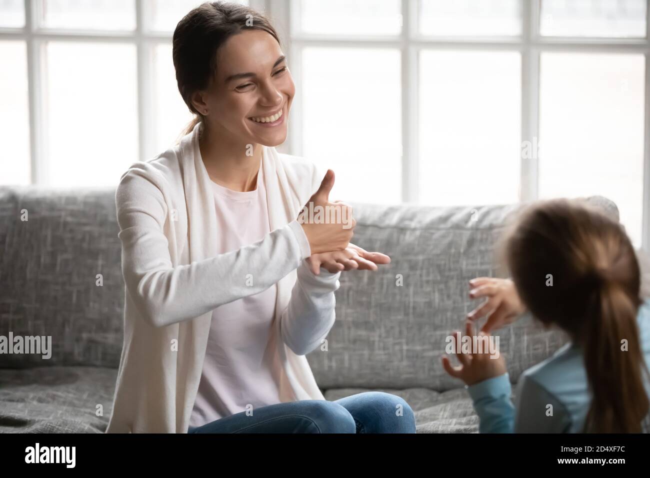 Smiling mom use sign language talking with small daughter Stock Photo