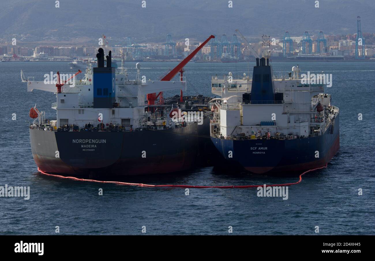 Oil tankers with anti pollution boom around them in Gibraltar harbour Stock Photo