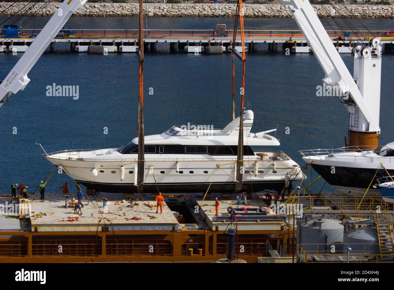 Luxury power boat / yacht being loaded onto a barge in Gibraltar harbour for transport or delivery Stock Photo